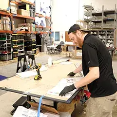 Trade show booth fabricator assembling display components in a warehouse.
